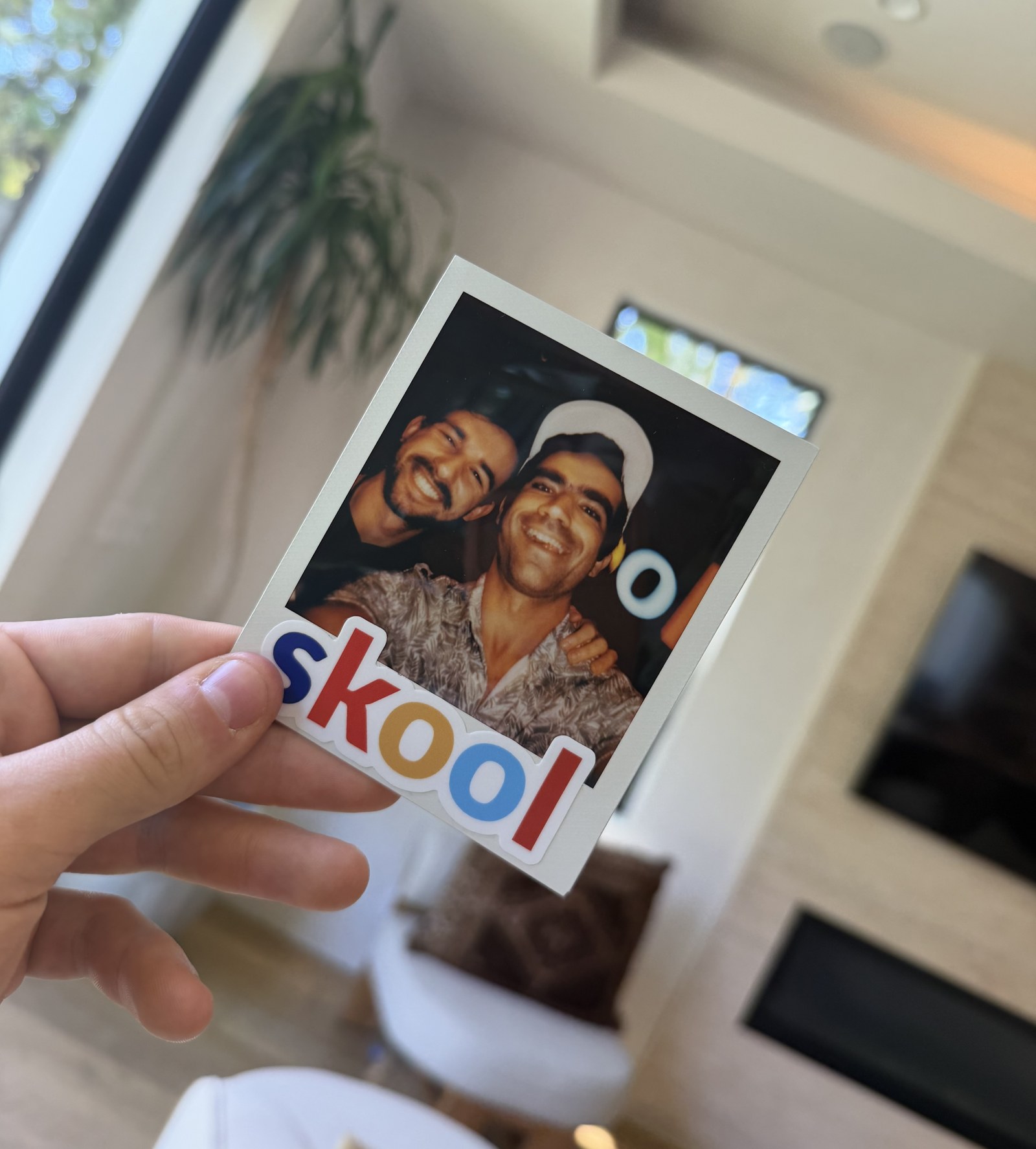 Una fotografía instantánea de dos personas con una pegatina de Skool, sostenida frente a la cámara